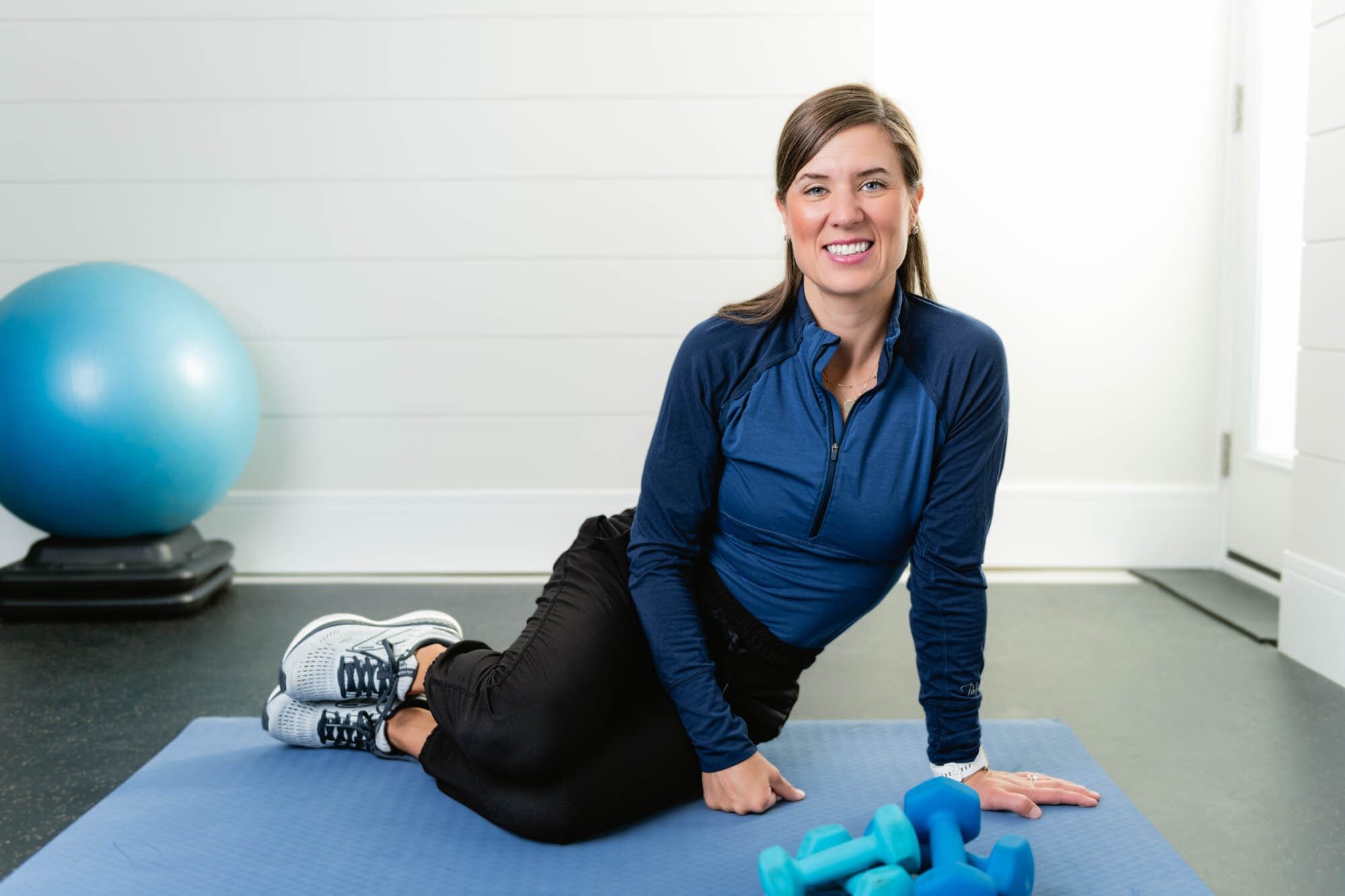stonger at home-1 Woman exercising on a yoga mat with dumbbells.