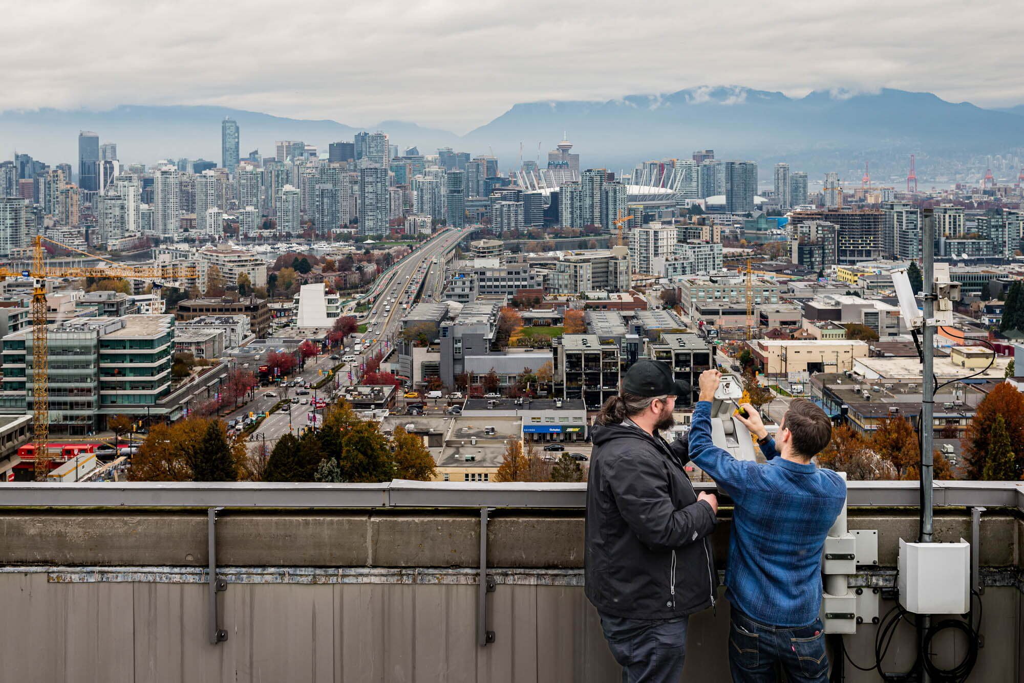 Rose Security-9 Technicians working with camera over vancouver city skyline in background.