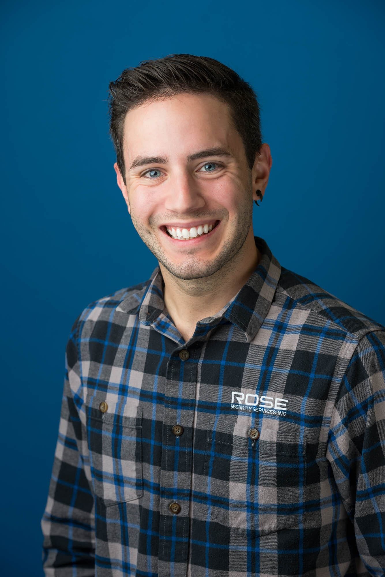 Rose Security Headshots-2 Smiling person wearing a plaid shirt.
