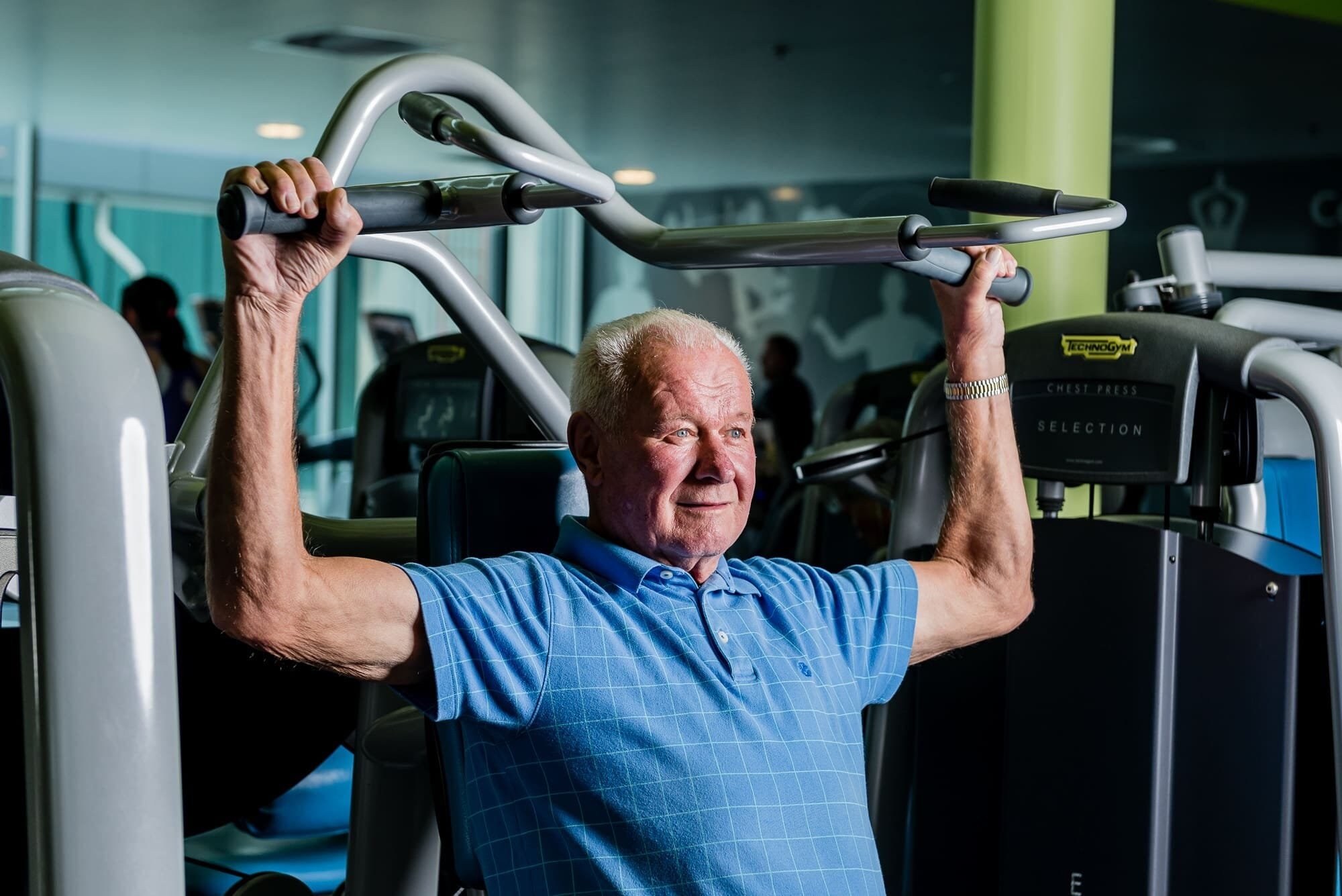 BAP_9164 Older man using chest press machine at gym.