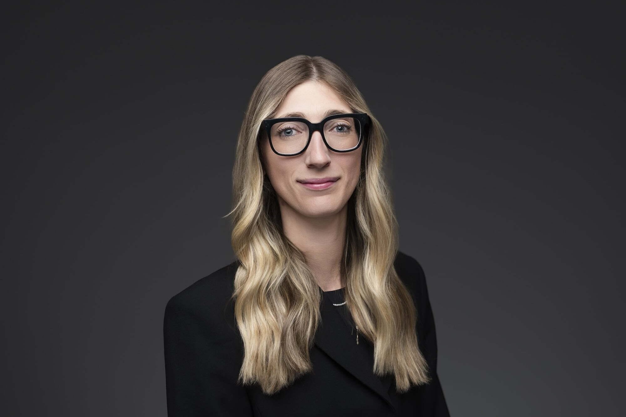 Anderson_Cori_482-0084--retouched Person with glasses smiling, wearing black blazer.