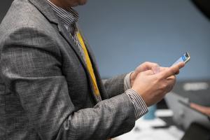 Person using smartphone in business suit.